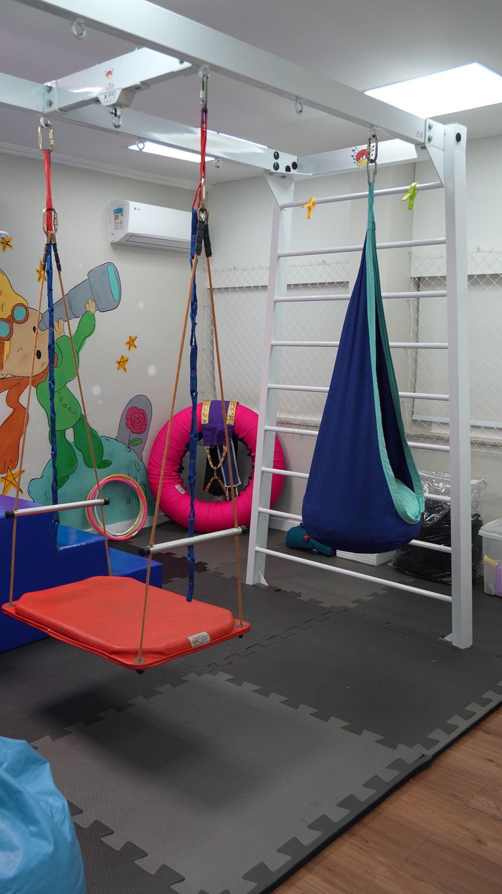 Sala sensorial com balanço, rede azul e colchonetes